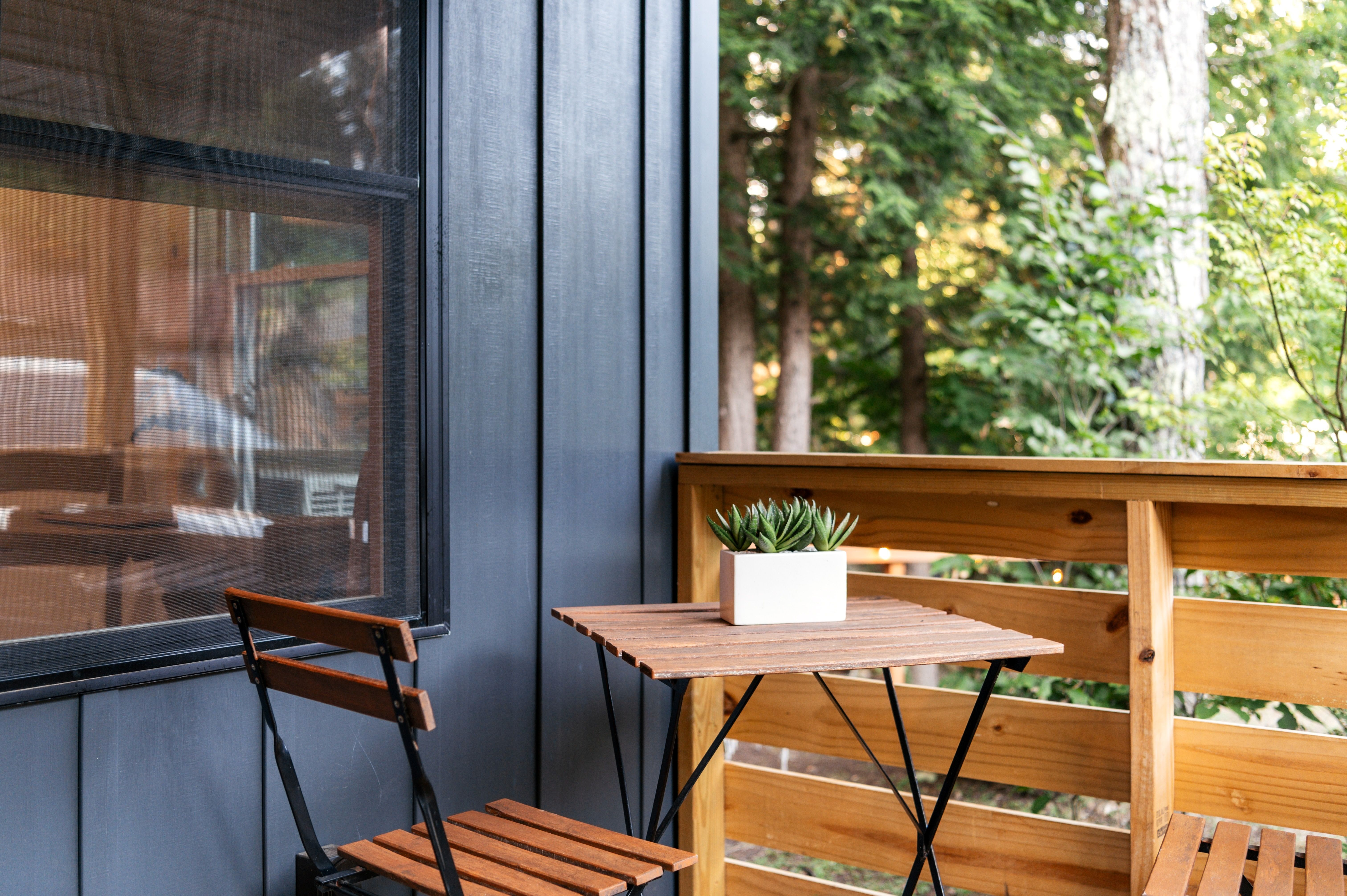 Small wooden patio with a chair, table, and potted succulent